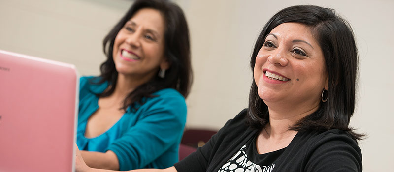 Two females sitting in class smiling