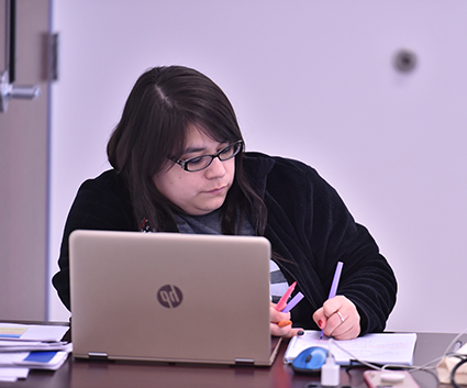 Female student writing with markers next to laptop