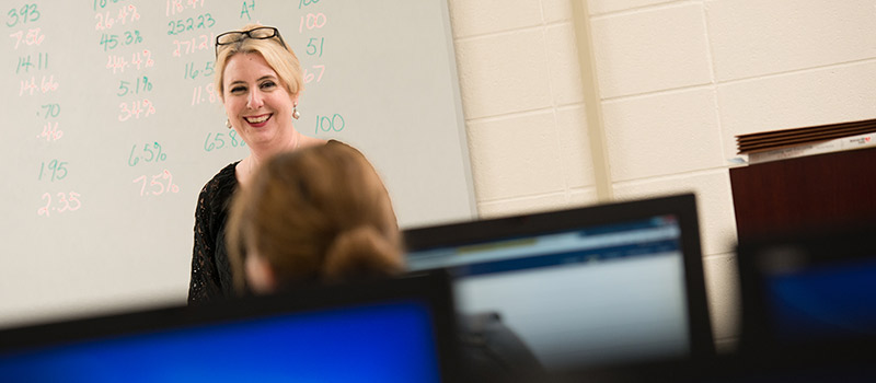 Female professor standing in front of classroom smiling