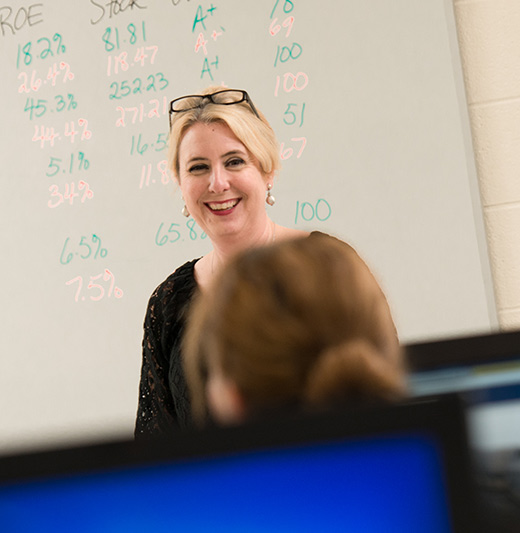 Female professor standing in front of classroom smiling