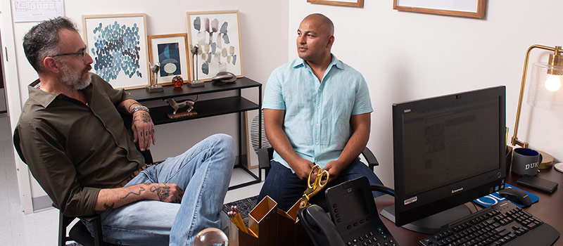 Male professor and male student sitting in office talking